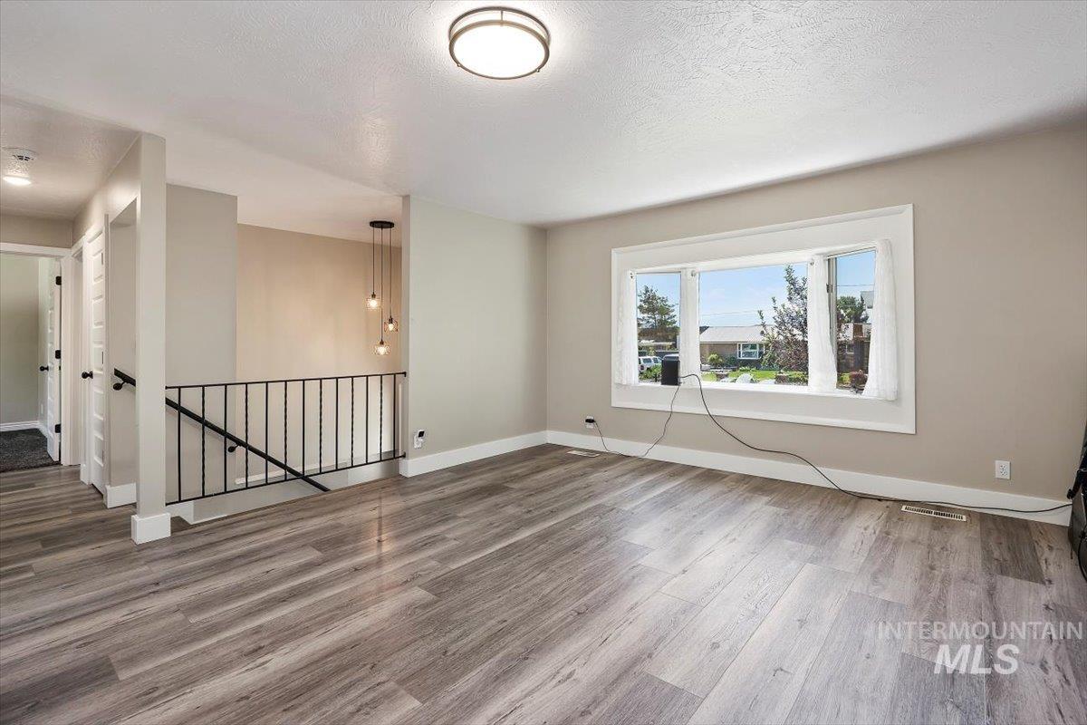616 Doris Avenue Paul, ID 83347 - Photo 9 of 38 Empty room featuring wood finished floors and a textured ceiling