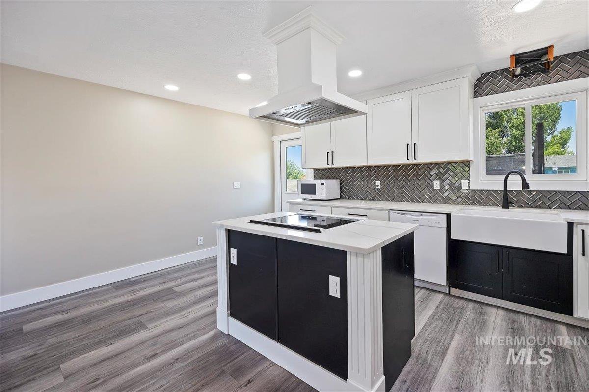 616 Doris Avenue Paul, ID 83347 - Photo 11 of 38 Kitchen with white appliances, light wood-style flooring, backsplash, light countertops, and a center island