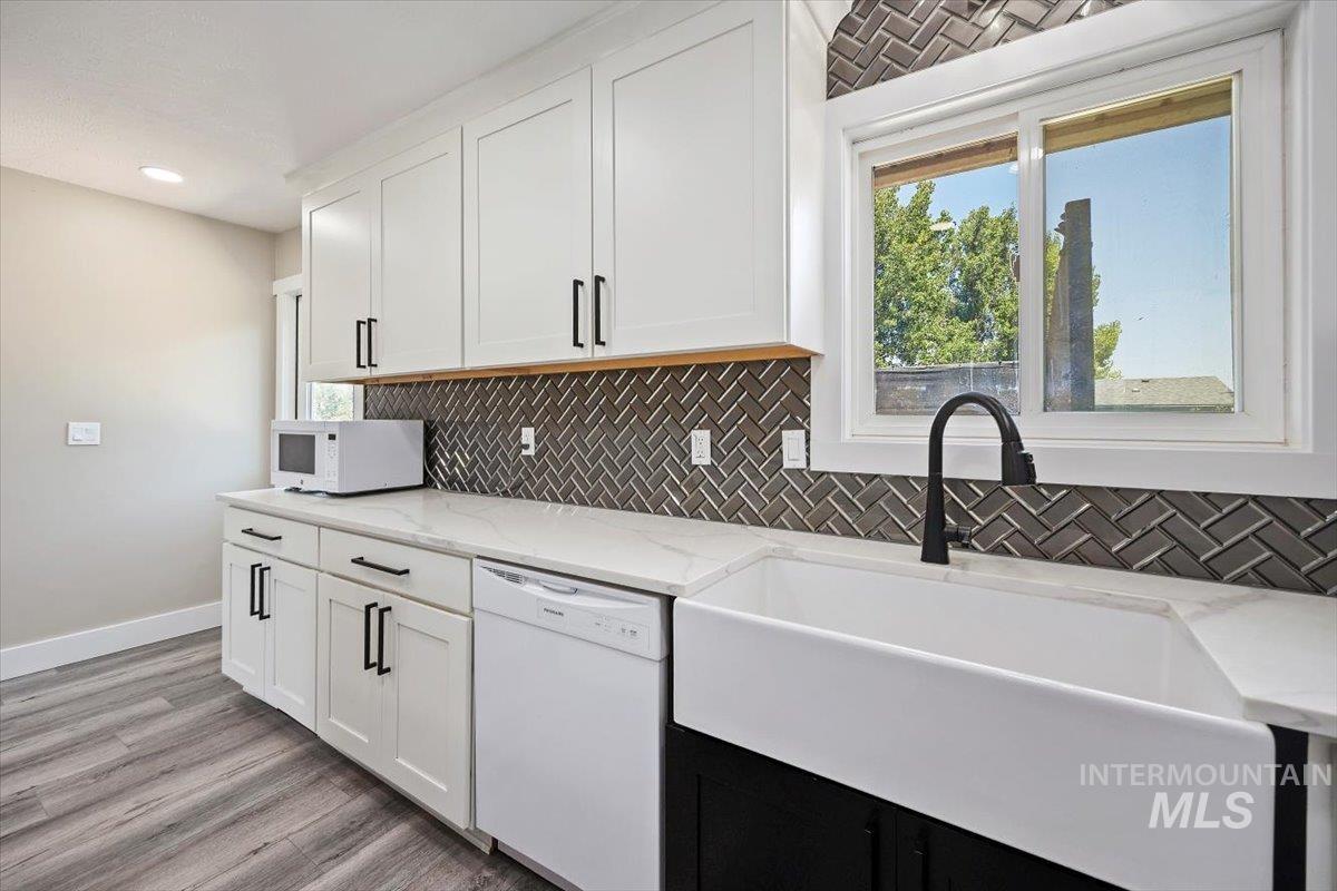 616 Doris Avenue Paul, ID 83347 - Photo 18 of 38 Kitchen featuring white appliances, tasteful backsplash, white cabinetry, light stone counters, and light wood-type flooring