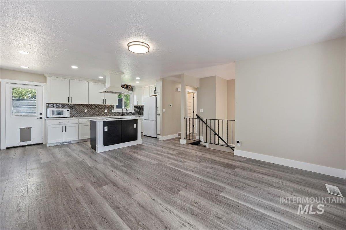 616 Doris Avenue Paul, ID 83347 - Photo 7 of 38 Kitchen with light wood-style floors, light countertops, a kitchen island, white cabinets, and backsplash