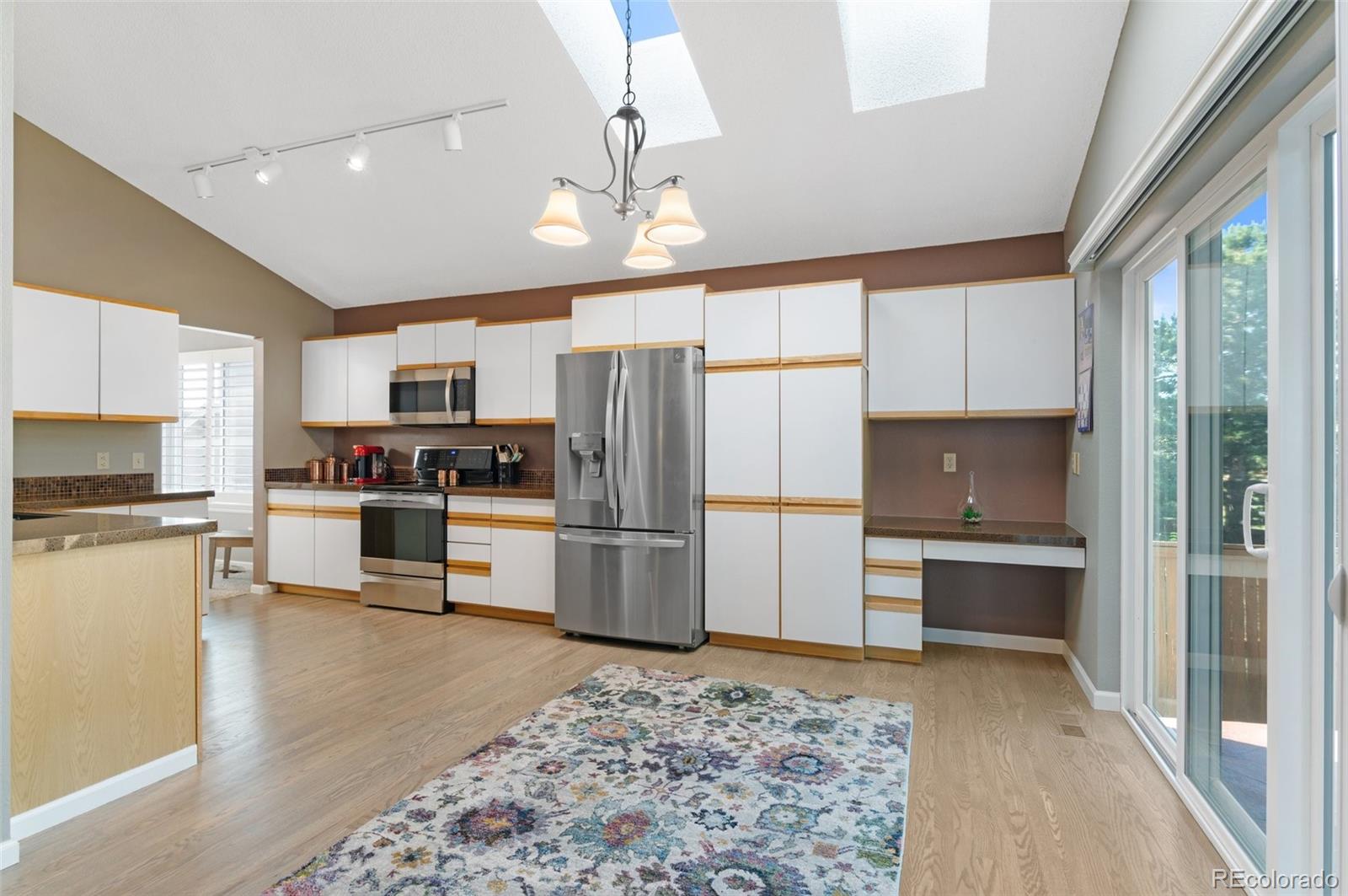 9836 Buckingham Court Highlands Ranch, CO 80130 - Photo 16 of 42 a kitchen with refrigerator a oven and white cabinets with wooden floor