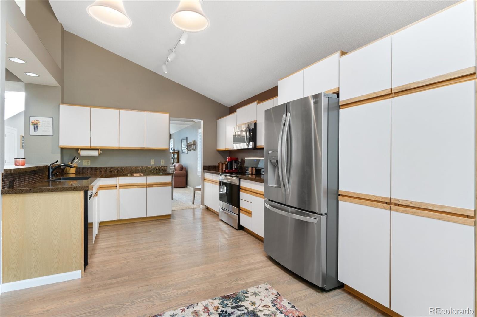 9836 Buckingham Court Highlands Ranch, CO 80130 - Photo 18 of 42 a kitchen with a refrigerator a sink and cabinets
