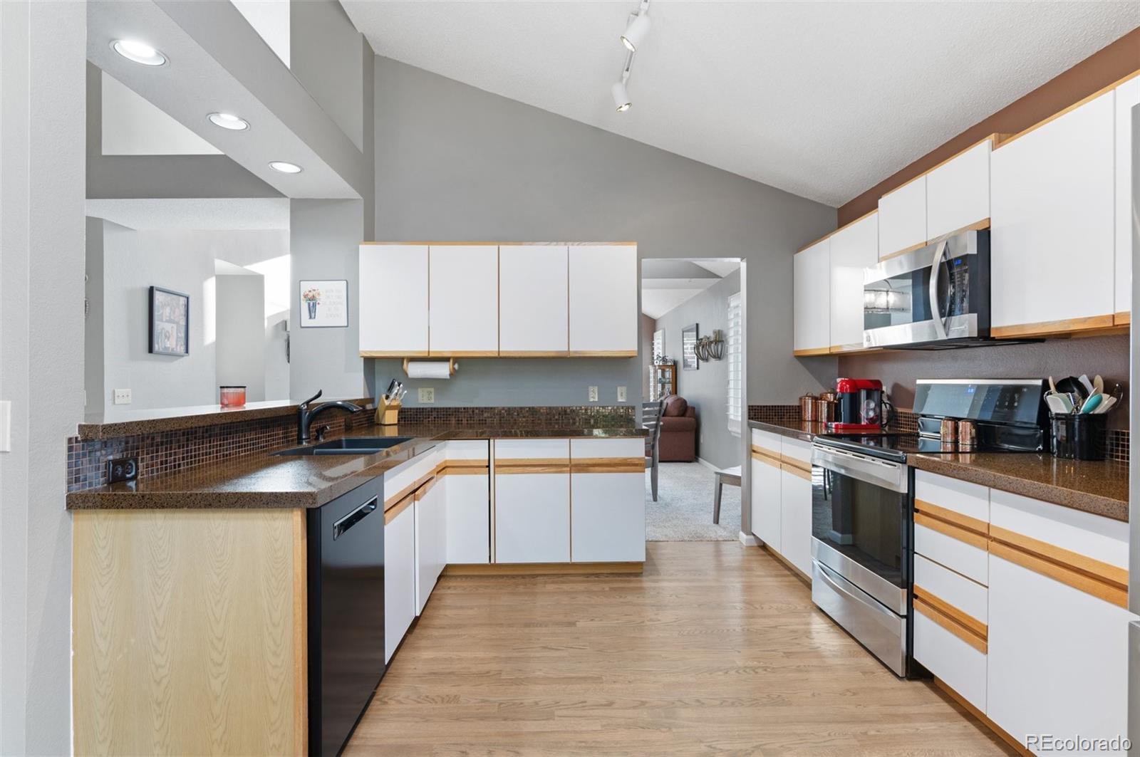 9836 Buckingham Court Highlands Ranch, CO 80130 - Photo 19 of 42 a kitchen with stainless steel appliances granite countertop a sink and stove top oven