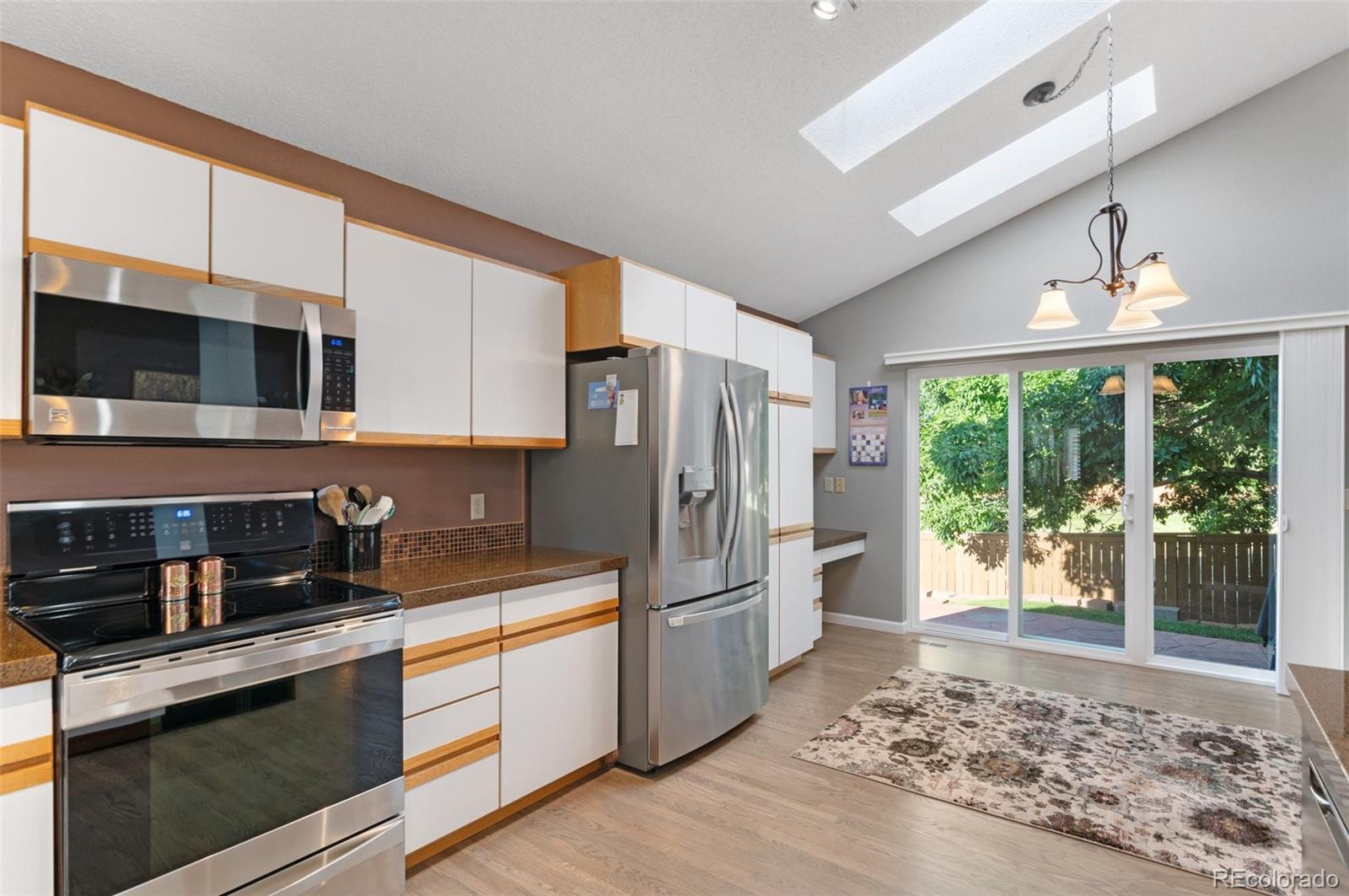 9836 Buckingham Court Highlands Ranch, CO 80130 - Photo 22 of 42 a kitchen with stainless steel appliances granite countertop a refrigerator a stove a sink and white cabinets with wooden floor