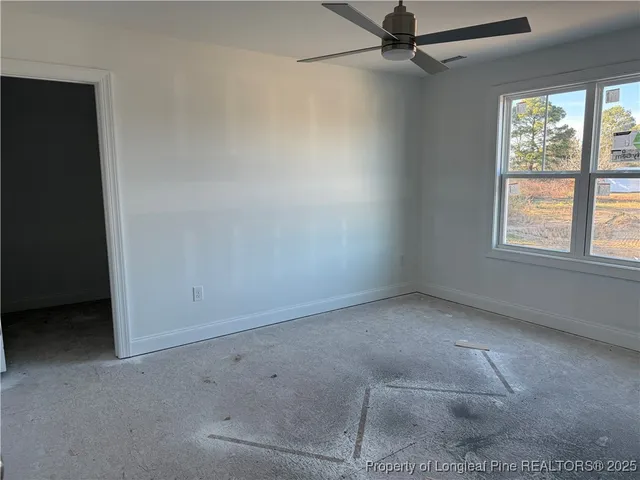 an empty room with a windows and ceiling fan