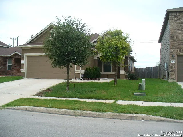 a view of a house with a yard and a large tree