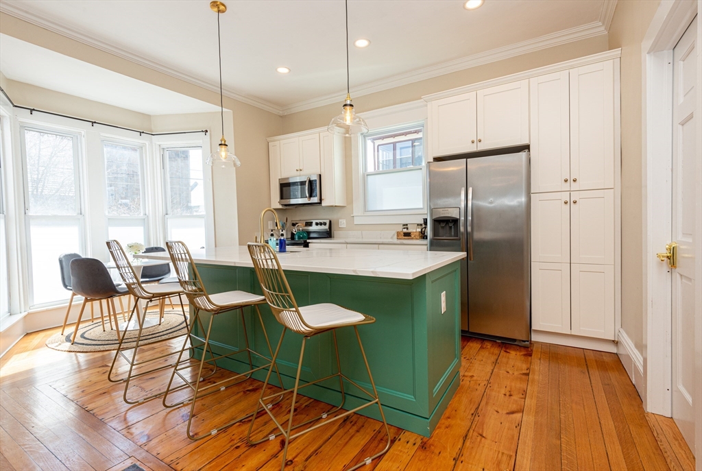 a kitchen with stainless steel appliances granite countertop a table chairs and a refrigerator