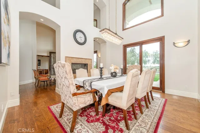 a open kitchen with stainless steel appliances granite countertop a refrigerator a stove a sink dishwasher a dining table and chairs with wooden floor