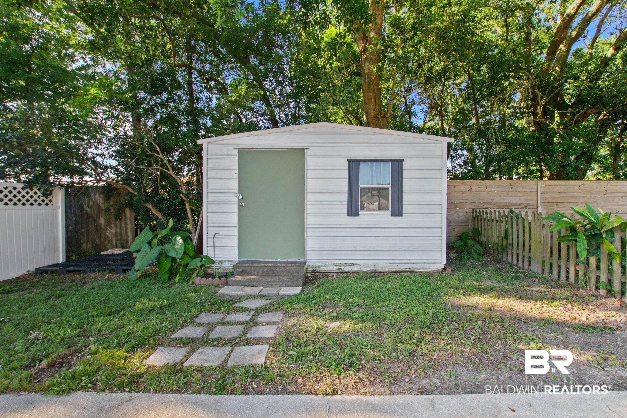524 Ariel Avenue Foley, AL 36535 - Photo 29 of 37 Detached storage shed featuring a green door, an operable window with dark shutters, and a small concrete stoop
