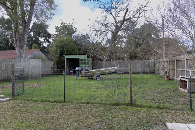 a view of a backyard with a slide trees and wooden fence