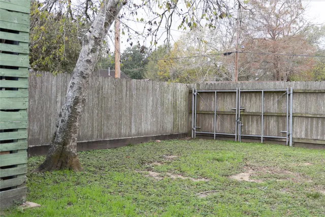 a view of backyard with wooden fence and large trees