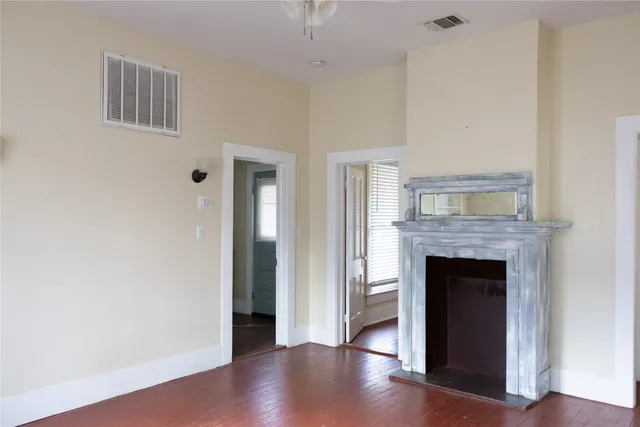 a view of an empty room with wooden floor and a fireplace