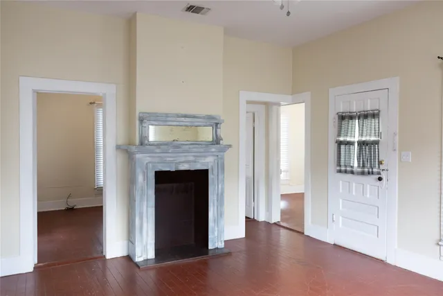 a view of an empty room with wooden floor and a fireplace