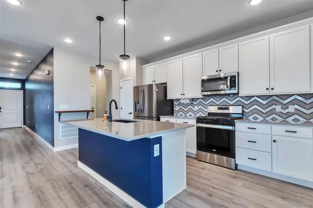 a kitchen with kitchen island granite countertop stainless steel appliances a refrigerator a sink and wooden cabinets