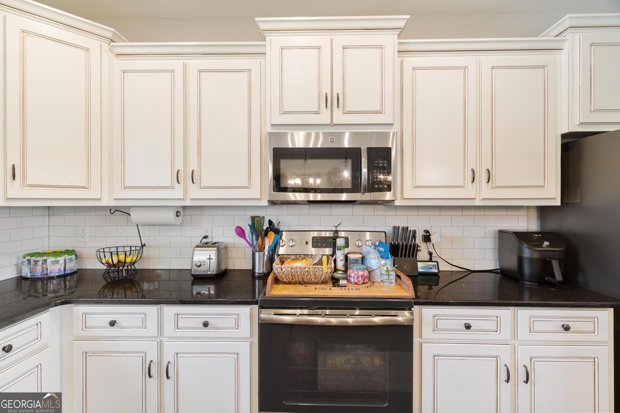 1287 Idlewood-Munnerlyn Road Waynesboro, GA 30830 - Photo 11 of 48 a kitchen with white cabinets and black appliances