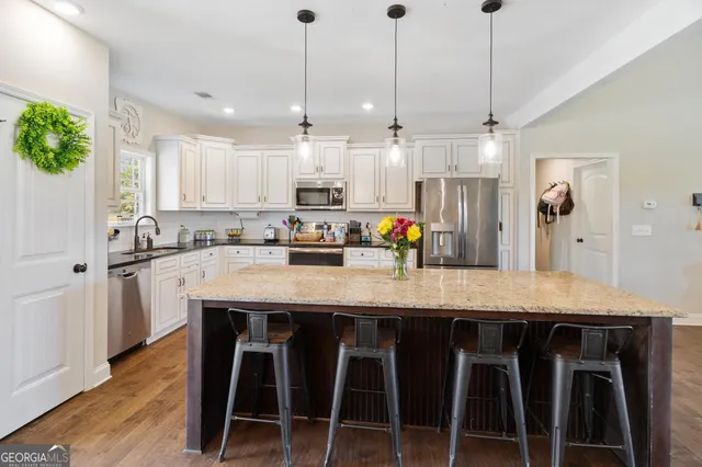 a kitchen with stainless steel appliances granite countertop a stove a refrigerator and a dining table with wooden floor