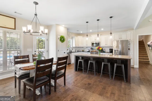 a dining area with furniture a chandelier and kitchen view