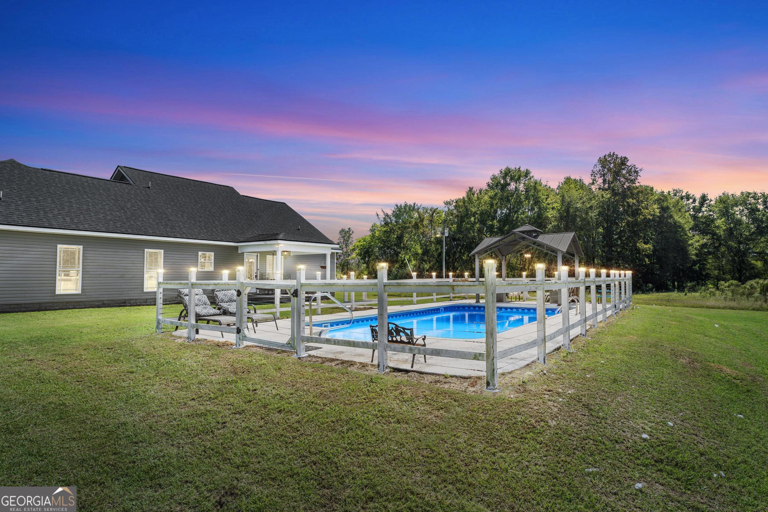 1287 Idlewood-Munnerlyn Road Waynesboro, GA 30830 - Photo 2 of 48 a view of a swimming pool with a table and chairs