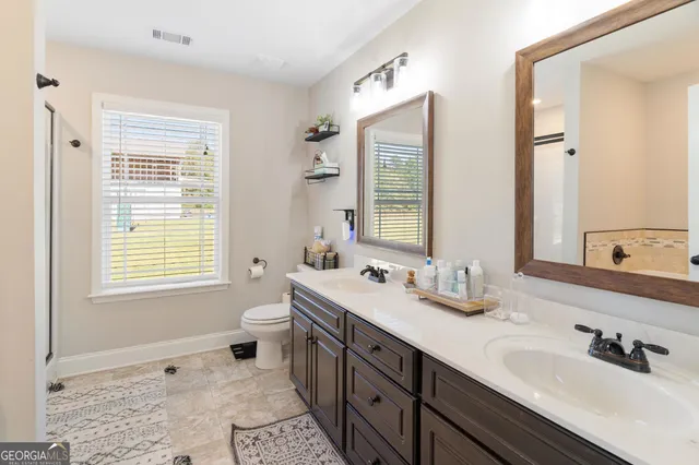 a bathroom with a double vanity sink a toilet and a mirror