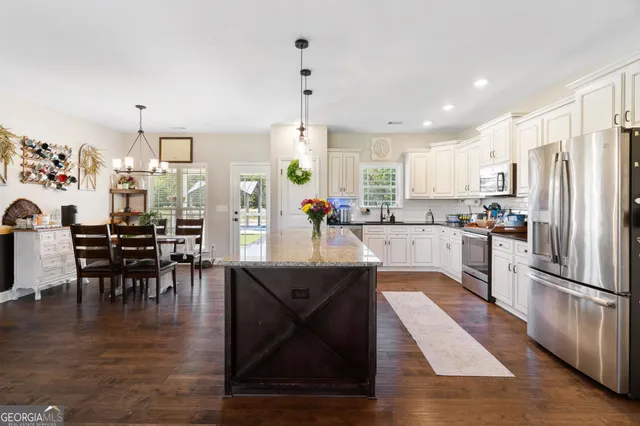a kitchen with stainless steel appliances granite countertop a table chairs and a refrigerator