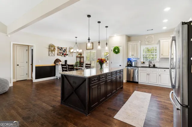 a large kitchen with stainless steel appliances a large counter top a stove a sink and a refrigerator