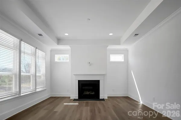 a view of an empty room with wooden floor fireplace and a window