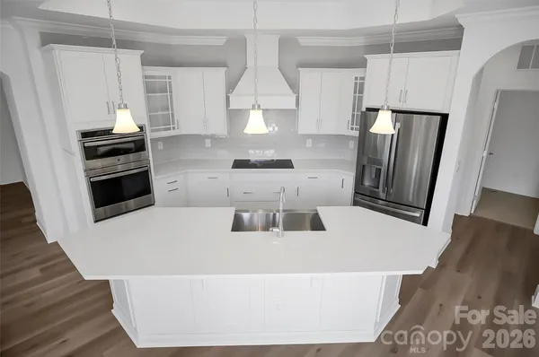 a kitchen with stainless steel appliances a refrigerator a stove a sink and white cabinets
