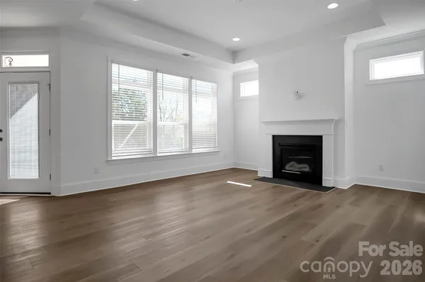 an empty room with wooden floor fireplace and windows