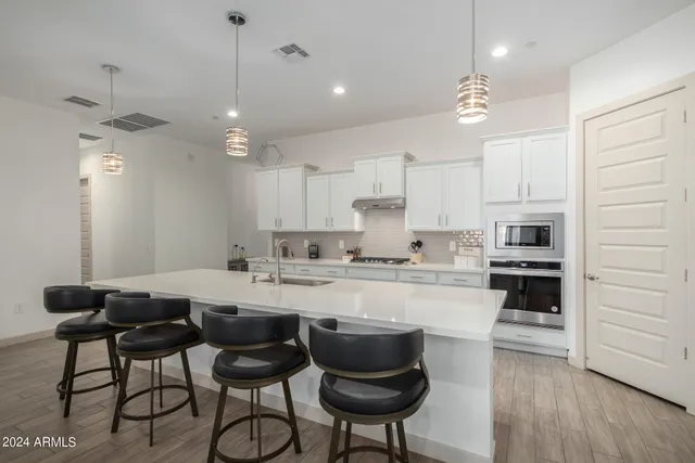 a kitchen with kitchen island granite countertop a dining table chairs cabinets and stainless steel appliances