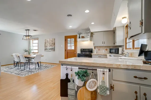 a kitchen with stainless steel appliances granite countertop a sink a stove a dining table and chairs