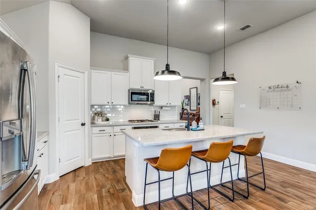 a kitchen with stainless steel appliances kitchen island granite countertop a stove a sink a refrigerator and chairs