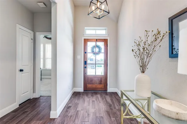 a view of a hallway with wooden floor and a bathroom