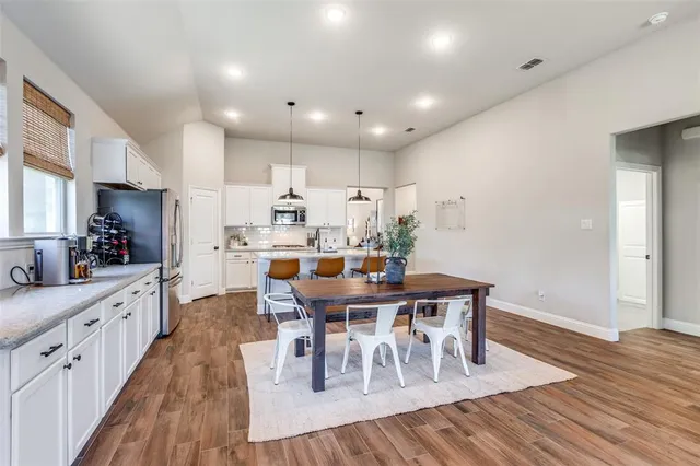 a open dining room with stainless steel appliances a table and chairs