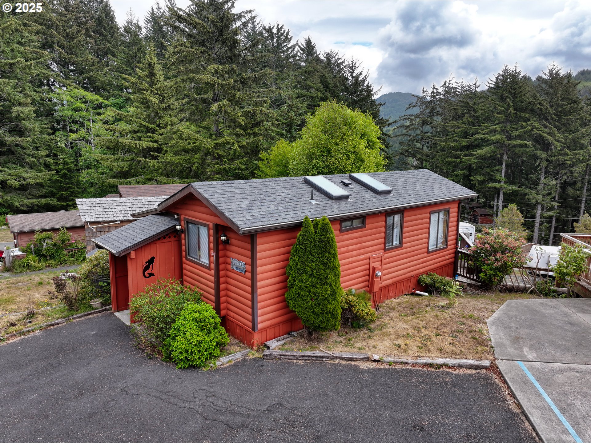 19921 Whaleshead Road, Unit M2 Brookings, OR 97415 - Photo 2 of 29 a view of a house with a yard plants and large tree