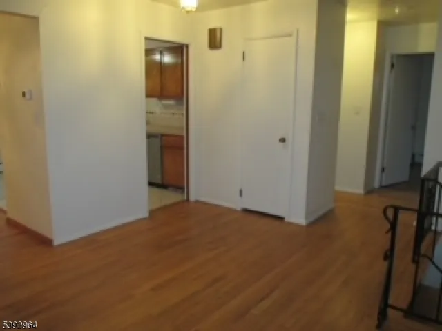 a view of an empty room with wooden floor and a bathroom