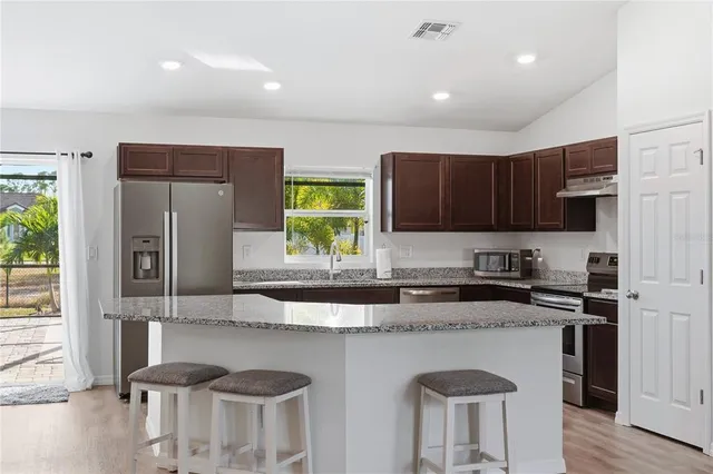a kitchen with stainless steel appliances granite countertop sink stove top oven and refrigerator