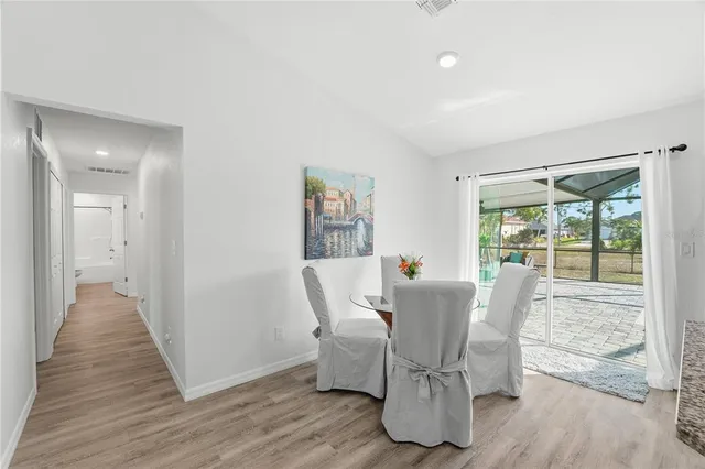 a kitchen with stainless steel appliances kitchen island granite countertop a refrigerator a stove top oven a sink and a dining table with wooden floor