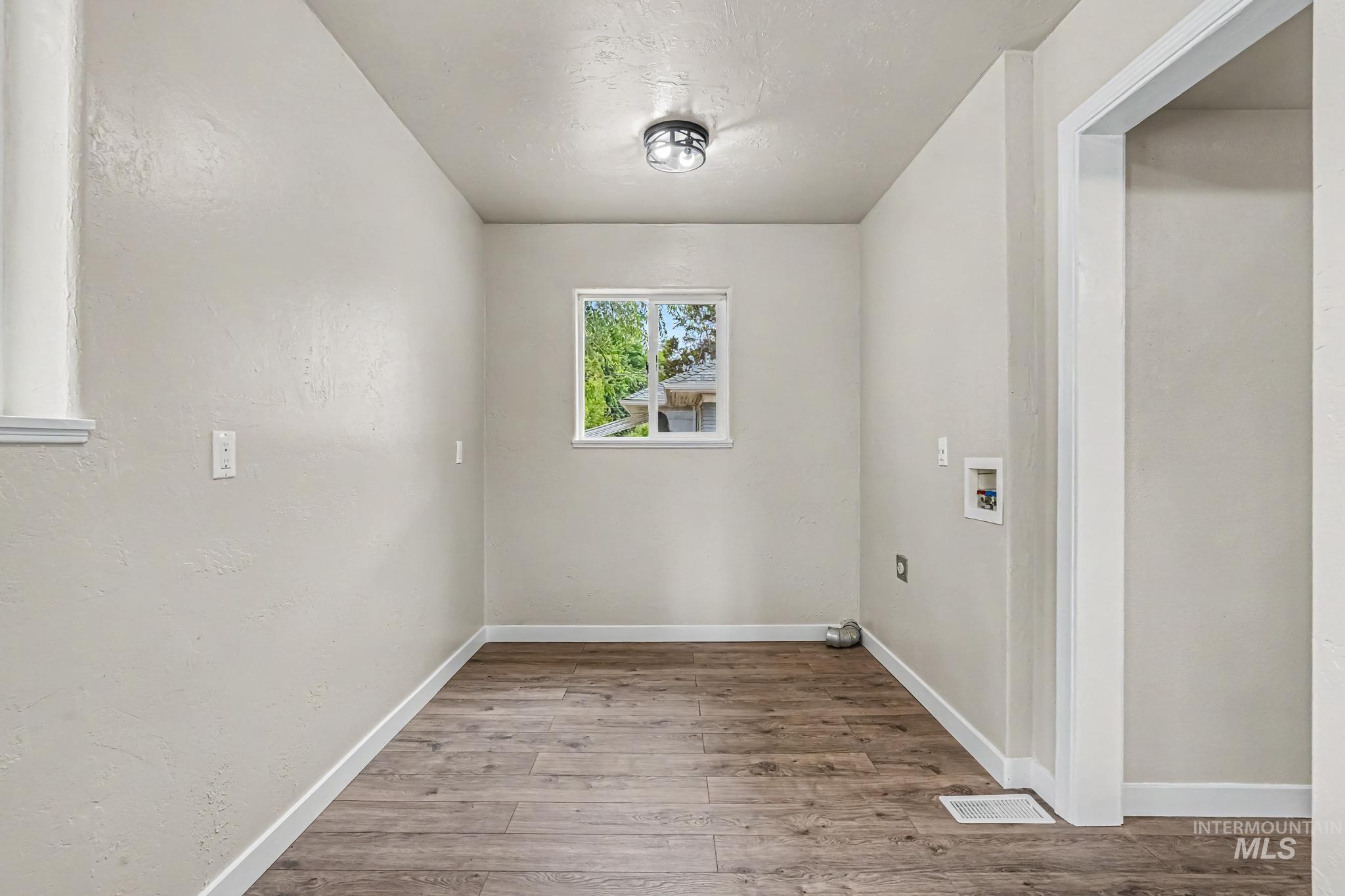 1023 State Street Weiser, ID 83672 - Photo 14 of 25 Dedicated utility space featuring wood-finish flooring, light neutral wall tones, and a window for natural illumination