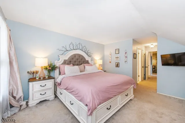 a spacious bedroom with a bed and a flat screen tv