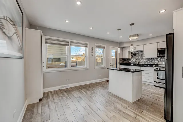 a kitchen with white cabinets and wooden floor