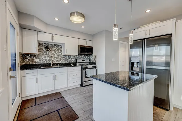 a kitchen with stainless steel appliances granite countertop a sink a stove a refrigerator and a granite counter tops