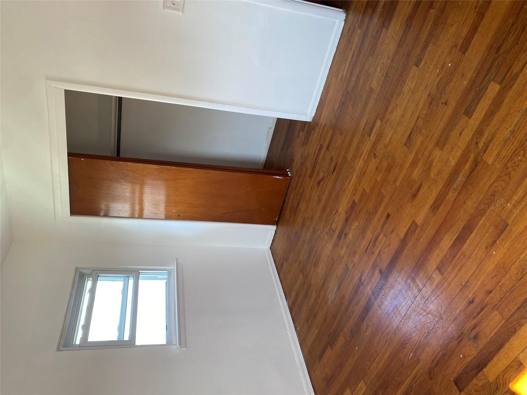 129-32 145th Street Queens, NY 11436 - Photo 9 of 15 a view of an empty room with wooden floor and closet