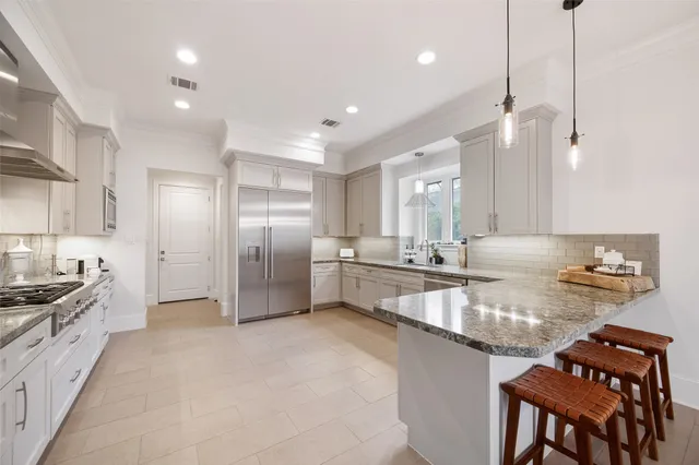 a large kitchen with kitchen island a large counter top stainless steel appliances and cabinets