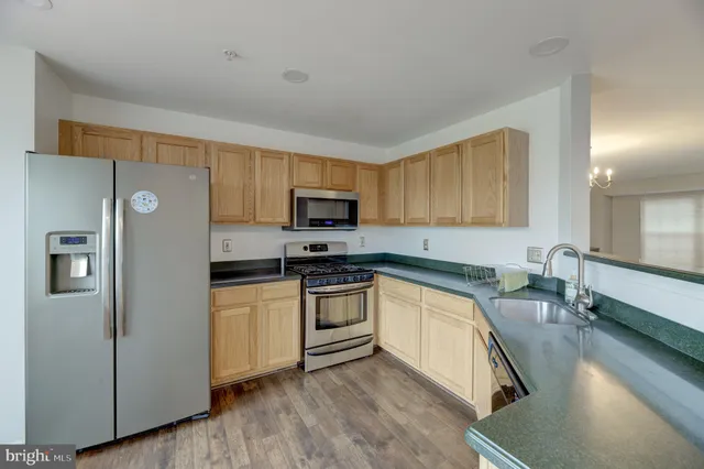 a kitchen with stainless steel appliances granite countertop a refrigerator a stove top oven a sink and dishwasher