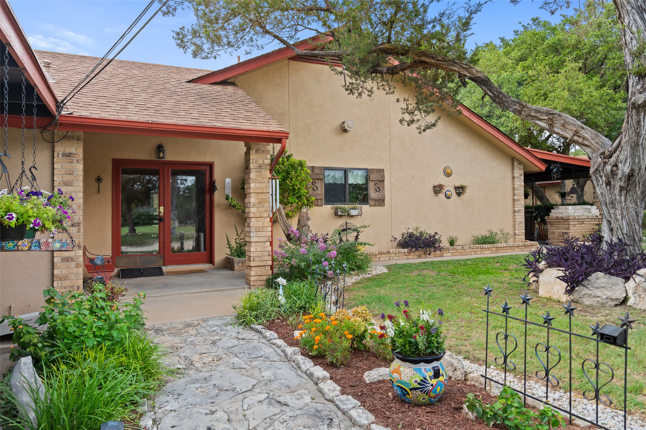 23200 Fulkes Road Leander, TX 78641 - Photo 2 of 15 A welcoming stone pathway leads to a charming stucco home framed by lush garden beds and mature trees.