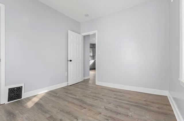 a view of an empty room with wooden floor and closet