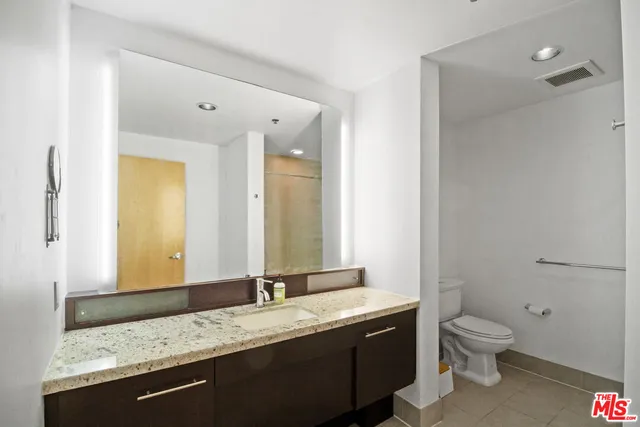 a bathroom with a granite countertop sink a mirror and shower