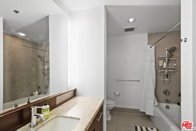 a bathroom with a granite countertop sink a toilet and a mirror
