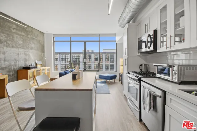 a kitchen with stainless steel appliances granite countertop a stove top oven a sink a dining table and chairs