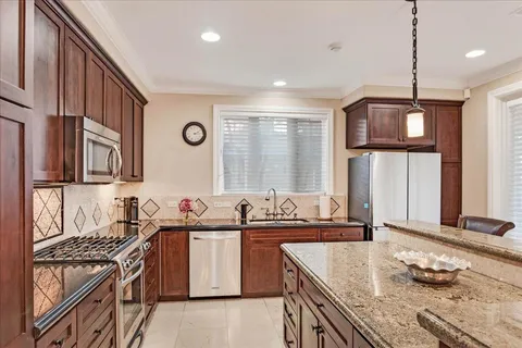 a kitchen with a stove a sink a center island and a wooden cabinets